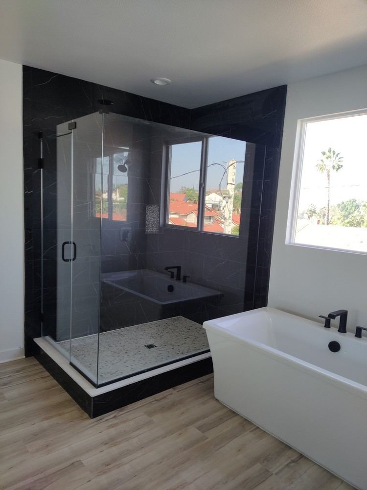 GiLand Inc. custom walk-in shower with black-frame glass enclosure and freestanding soaking tub